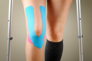 Athlete standing on crutches after ATC tapes her knee.