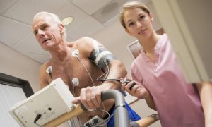 Exercise physiologist intern monitoring cardiac rehab patient during graded stress test.