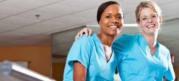 Two female physical therapy assistants taking a break from work and posing for photo inside a rehabilitation clinic.