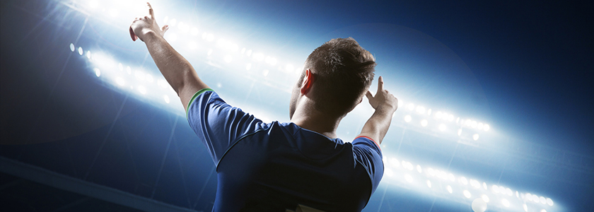 World famous soccer player during night game pointing to his sports marketing team in the stands.